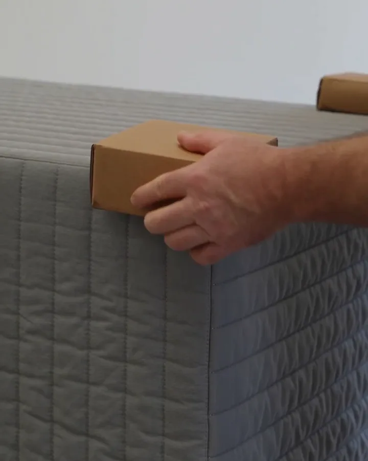 Pose de protections d'angle en carton sur un meuble enveloppé de couvertures matelassées