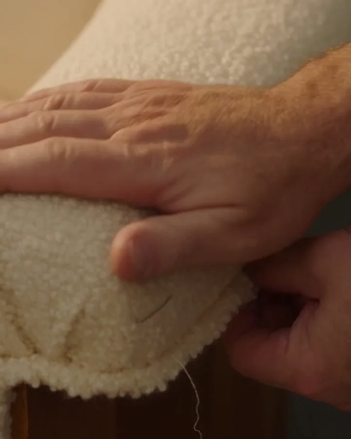 Pose d'un tissu bouclé crème sur l'accoudoir d'un canapé